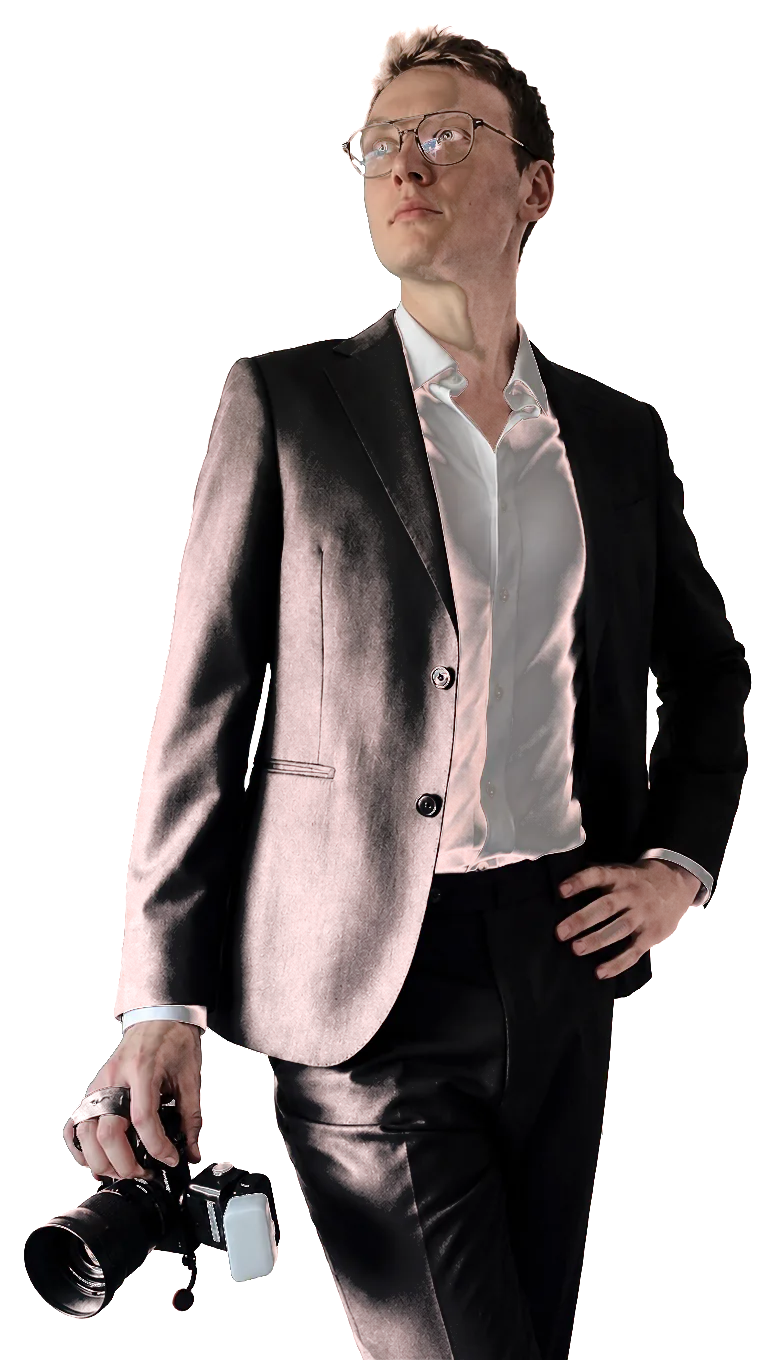 Mikkel, the photographer behind Nítid, in a suit holding a camera